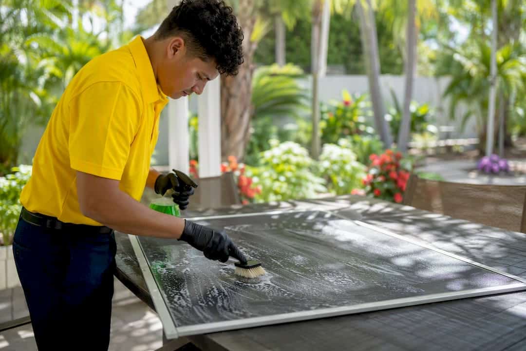 Cleaning professional scrubbing a removed window screen outdoors