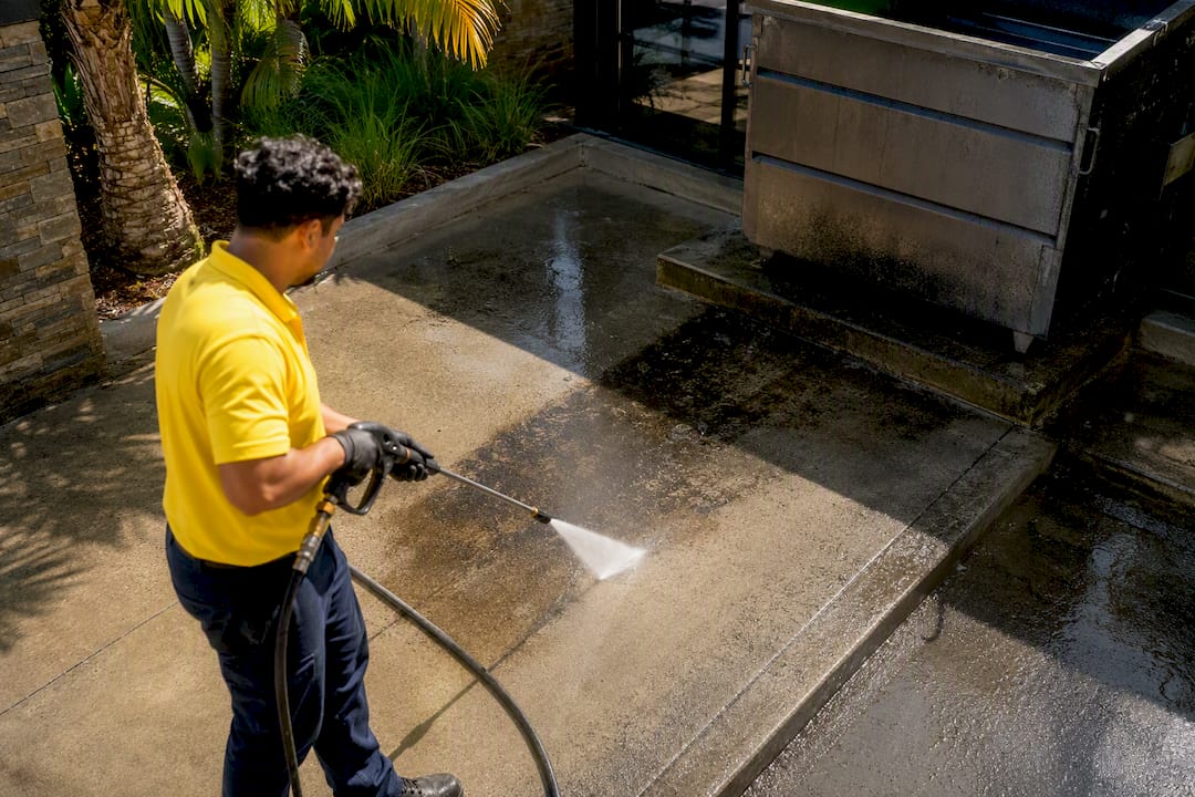 Worker power washing commercial grease stains